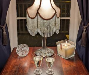 a table with glasses and a lamp and a candle at The 1890 Freeman House in Galveston +50 photos