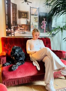 a woman sitting on a red couch with a black dog at Villa Utsikten in Tofte