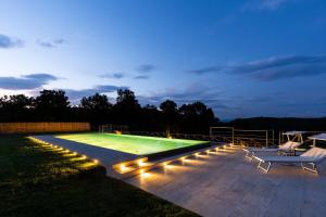 a swimming pool with lights in a backyard at night at Il Giuncheto in Trequanda