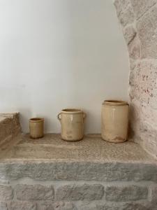 three buckets are sitting on a brick wall at Masseria La Mandra in Noci