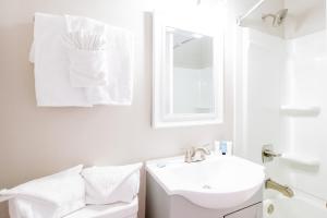 a white bathroom with a sink and a mirror at 300 Tenth in Myrtle Beach +30 photos