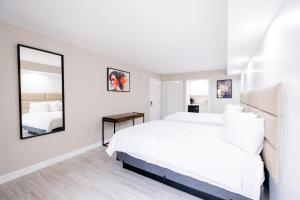 a white bedroom with a large bed and a mirror at 300 Tenth in Myrtle Beach