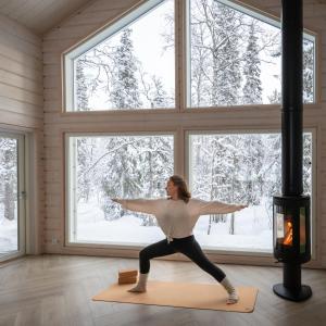 a woman practicing yoga in a room with a fireplace at Foxfires mini Boutique Hotel in Levi