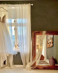 a mirror sitting next to a window with curtains at Villa Utsikten in Tofte