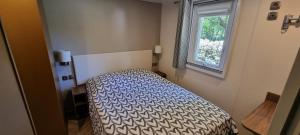 una camera da letto con un letto in una stanza con una finestra di Mobile home avec terrasse et piscine. a Hourtin
