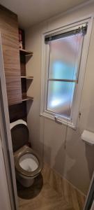 un piccolo bagno con servizi igienici e finestra di Mobile home avec terrasse et piscine. a Hourtin Altre 6 foto