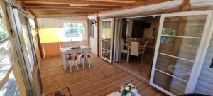 een afgeschermde veranda van een huis met een tafel en stoelen bij Mobile home avec terrasse et piscine. in Hourtin