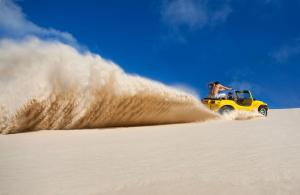 a man riding a yellow jeep in the sand at Holiday Inn Natal, an IHG Hotel in Natal