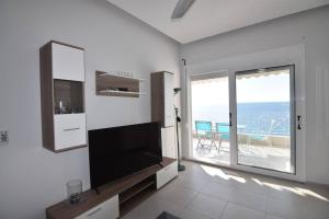 a living room with a tv and a large window at Magic Balcony on Siviri Chalkidiki. in Siviri