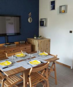 a wooden table with plates and wine glasses on it at Studio sur parc proche centre et télécabine in Briançon