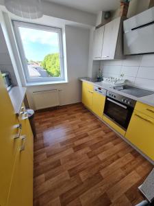 a kitchen with yellow cabinets and a large window at 6 bedroom Private APARTMENT & Lounge in Rostock