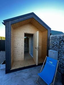 - un petit bâtiment en bois avec une chaise bleue devant dans l'établissement Morska Mila, à Gąski