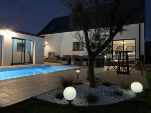 a backyard with a swimming pool and a tree at Maison 10 pers en bord de mer avec piscine chauffée toute l'année, spa et hamman in Surzur