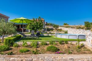 a garden with a table and a green umbrella at Holiday home Ante with beautiful private garden in Nadin
