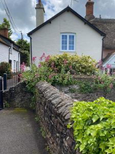 a stone wall in front of a house with flowers at Little House in Porlock