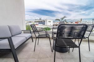 a patio with chairs and a couch on a balcony at INF42M- Modern city apartment, families only in Estepona