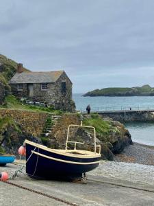 a boat sitting on the beach next to a house at Farm accommodation - The Lizard Peninsula, Cornwall in Helston