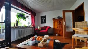 uma sala de estar com uma mesa e uma cadeira vermelha em Outdoor & Relax Blackforest em Neukirch