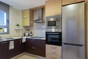 a kitchen with a stainless steel refrigerator and a microwave at El Capricho Terrassa. in Terrassa