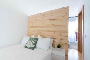 a bedroom with a white bed with a wooden wall at El Capricho Terrassa. in Terrassa +20 photos