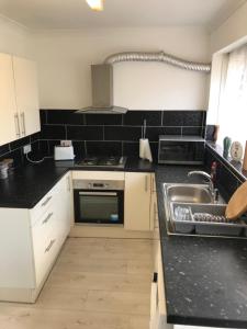 a kitchen with white cabinets and a sink at 2Bed Bungalow House, Speedwell, Bristol, UK, sleeps up to 6 guests in Bristol