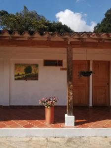 una casa con una pintura en la pared y un jarrón de flores en Hotel Ecoposada Viña de Aldana, en Los Santos