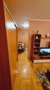 een woonkamer met een televisie en een tafel bij Apartman Lens in Novi Sad