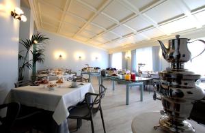 阿夏戈的住宿－Hotel Croce Bianca，一间带桌椅的餐厅和一间提供食物的房间