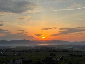 a sunset with the sun setting over a city at Domek Panorama in Lipowa
