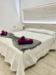 sypialnia z łóżkiem z fioletowymi ręcznikami w obiekcie ISLAND SUITES w Aronie