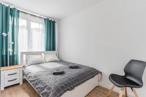 a bedroom with a bed and a black chair at Uroczy apartament 2 pokoje - 10 min do morza! in Gdańsk