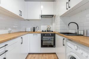 cocina blanca con fregadero y lavavajillas en Uroczy apartament 2 pokoje - 10 min do morza!, en Gdansk