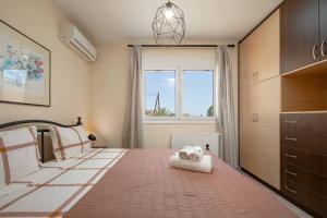 a bedroom with a large bed and a window at Villa Melenia for Family Holidays by the Beach in Agia Pelagia
