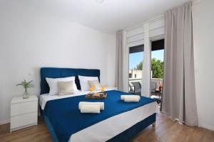 a white and blue bedroom with a blue bed at Bonaca apartments with terrace and private parking in Kaštela