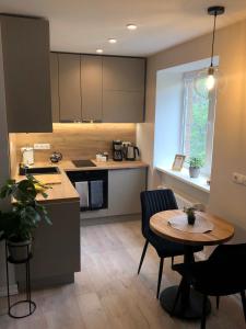 a kitchen with a small table and a table and a kitchen with a counter at Modern studio apartment near the beach - 5 min walk in Liepāja