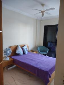 um quarto com uma cama roxa e uma cadeira azul em Apartamento Guarujá Enseada no Guarujá