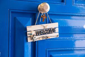 a welcome sign hanging on a blue door at Peters Studio in Archangelos