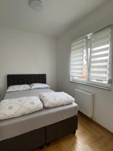 ein Schlafzimmer mit einem Bett und zwei Fenstern in der Unterkunft Apartman Lukana lll Banjaluka in Banja Luka