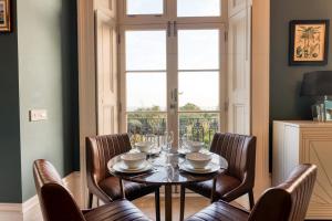 ein Esszimmer mit einem Tisch, Stühlen und einem Fenster in der Unterkunft The Regency - Sea views and a modern art deco style interior in Ramsgate