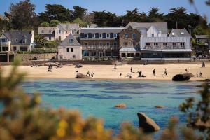 einen Strand mit Menschen auf dem Sand und Gebäuden in der Unterkunft Logis Hôtel Saint Guirec Et De La Plage in Perros-Guirec