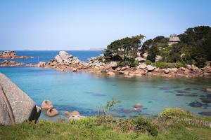 a large body of water surrounded by rocks and trees at Logis Hôtel Saint Guirec Et De La Plage in Perros-Guirec