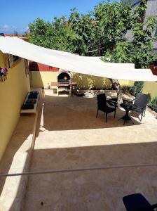 a white canopy over a patio with chairs and a table at LuMar Holidays and Apartments in Preko