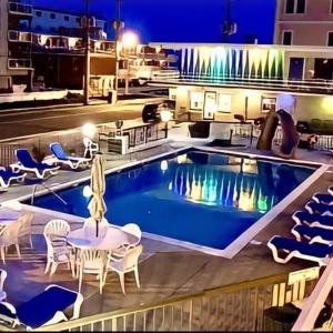 a pool on top of a building with tables and chairs at Beach Colony Motel in Wildwood Crest