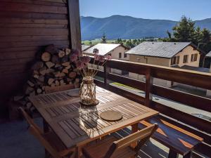 a wooden table on a balcony with a vase of flowers at Appartemment type chalet in Formiguères