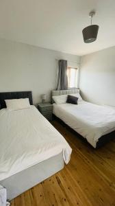 two beds in a room with wooden floors at Modern City Centre House in Galway