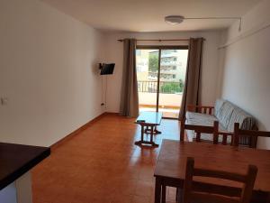 sala de estar con mesa, sillas y ventana en Apartamentos Es Cantó, en Playa d'en Bossa