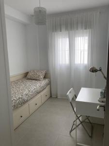 a white bedroom with a bed and a desk at APARTAMENTO SAN JUAN in Sanlúcar de Barrameda