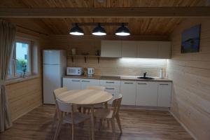 a kitchen with a table and chairs and a refrigerator at R&M Resort in Petkėniškės +23 photos