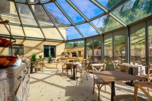 une véranda avec un plafond en verre, des tables et des chaises dans l'établissement Domaine de Ravat, à Sarlat-la-Canéda