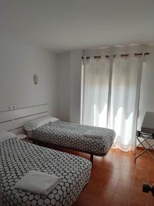 two beds sitting in a room with a window at Apartamentos Es Cantó in Playa d'en Bossa